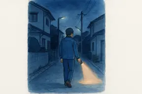 夜の住宅街の路地を懐中電灯で照らしながら歩く人の後ろ姿