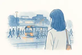 夜の駅ビルを背に帰宅する人波を見つめる女性の後ろ姿