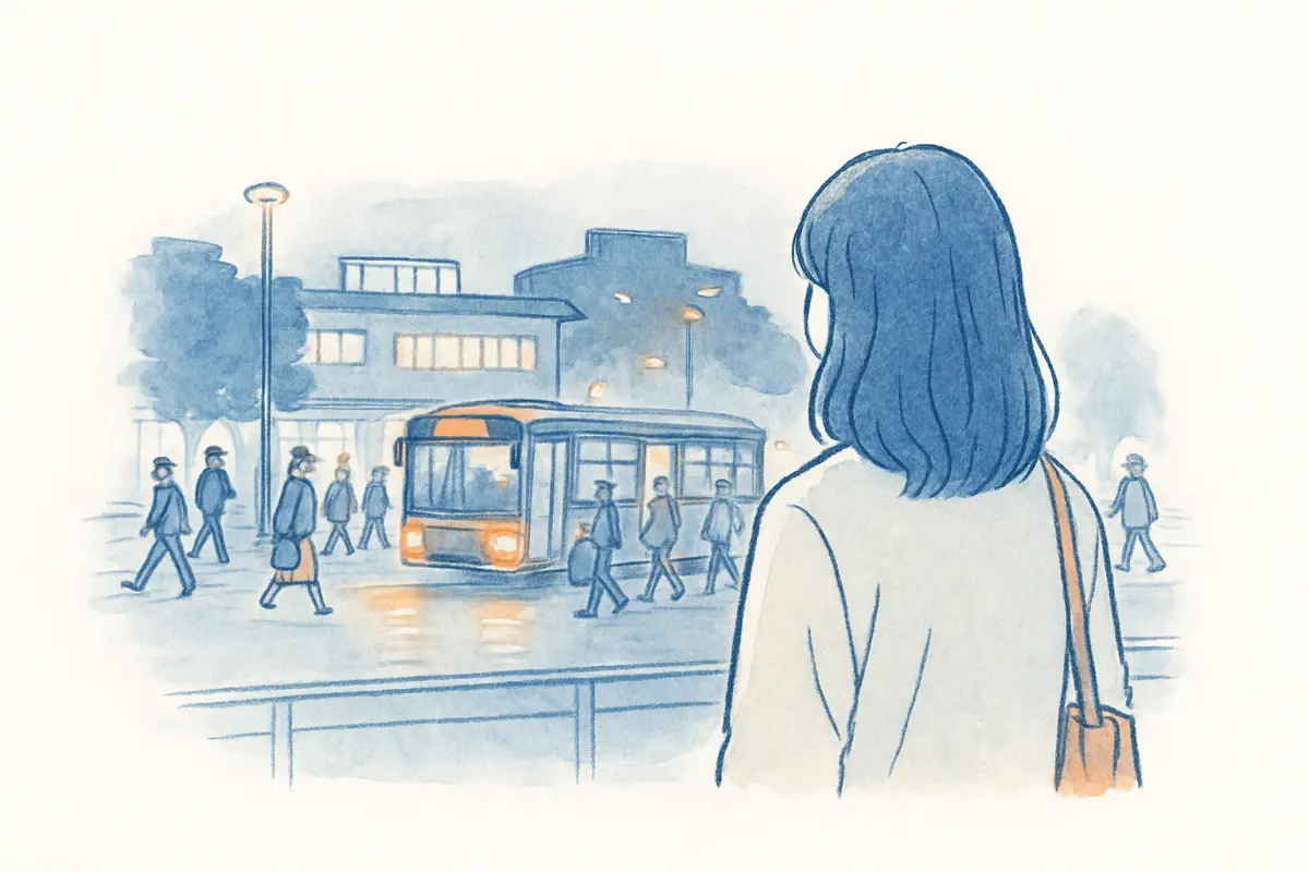 夜の駅ビルを背に帰宅する人波を見つめる女性の後ろ姿