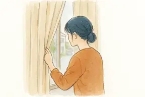 カーテンの隙間から外の様子をそっと確認する女性
